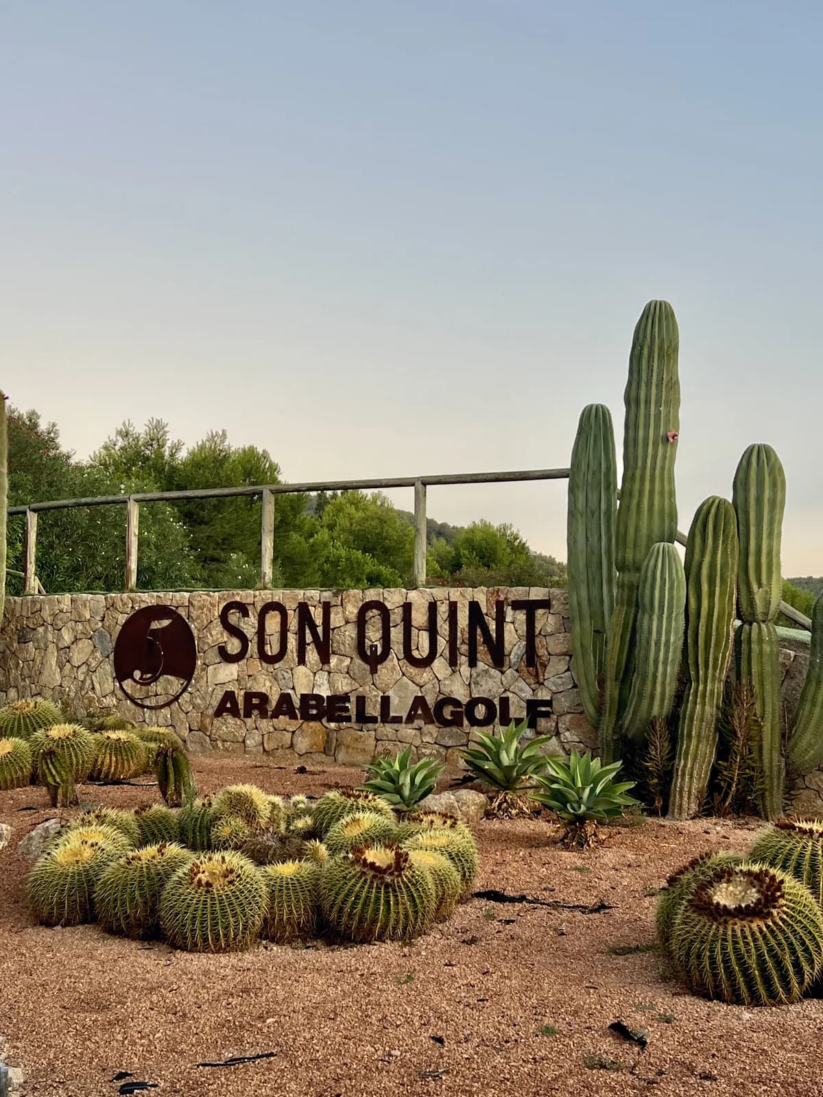 Stenskylt vid ingången till golfbanan Son Quint på Mallorca, omgiven av kaktusar