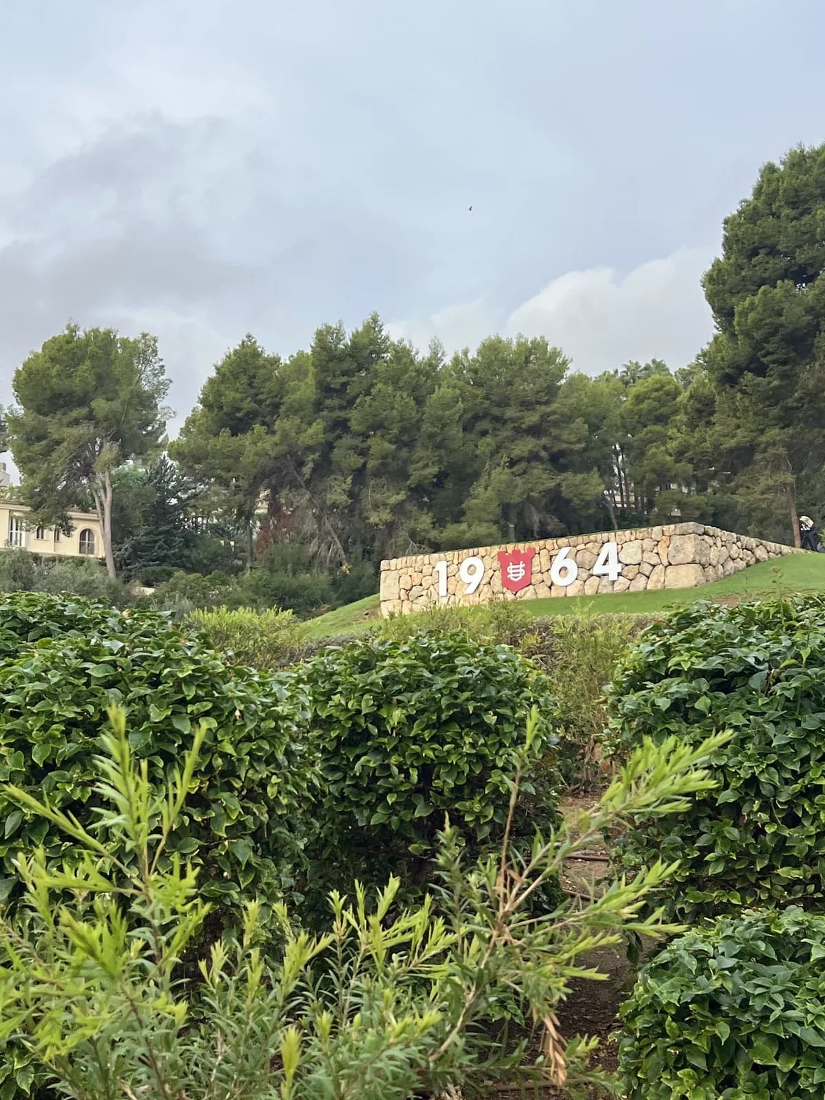 Stone wall marked 1964 with the Son Vida crest, among trees at Son Vida golf course Mallorca