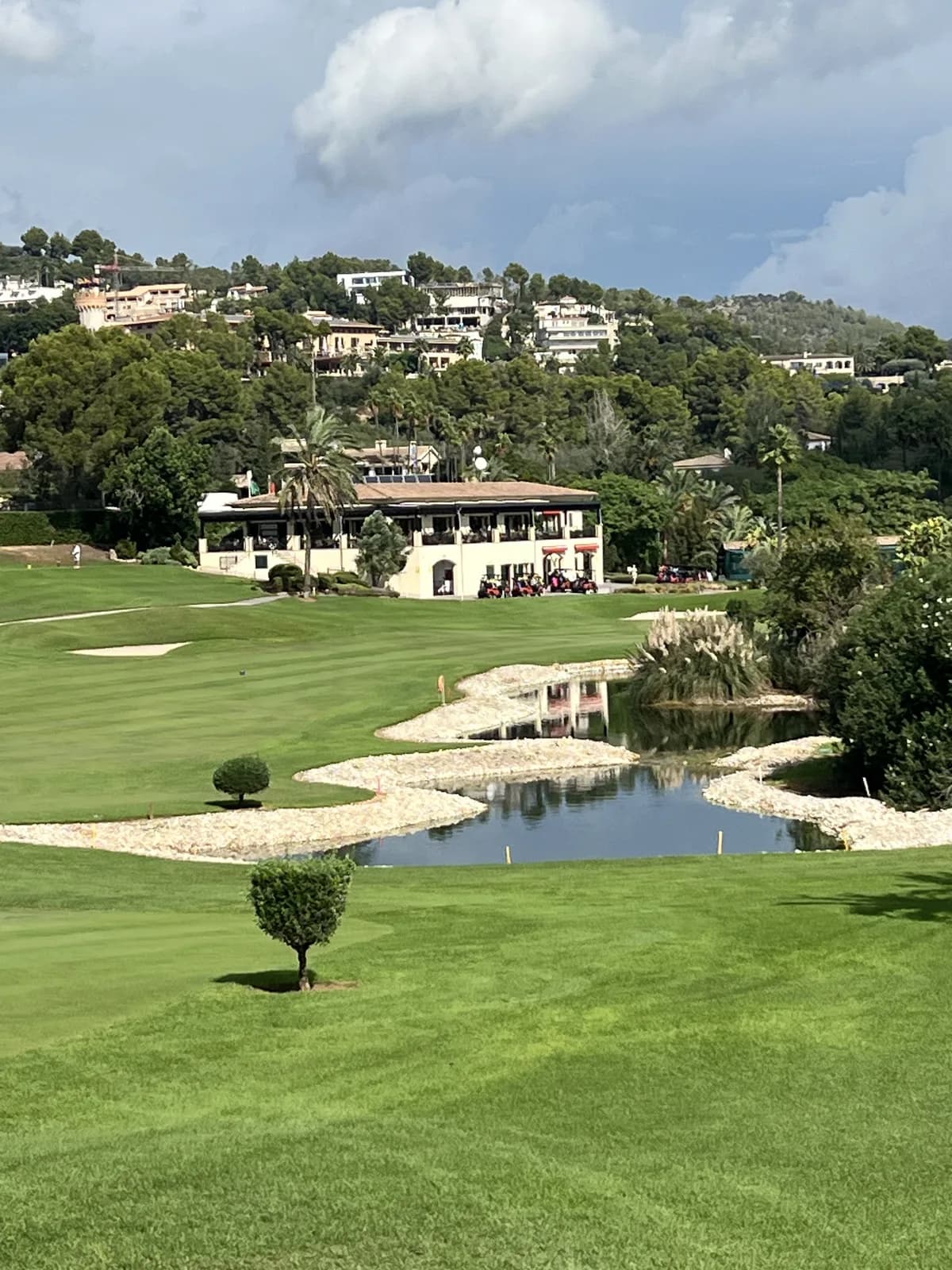 Water and rock edging in front of the Son Vida clubhouse with hillside villas behind