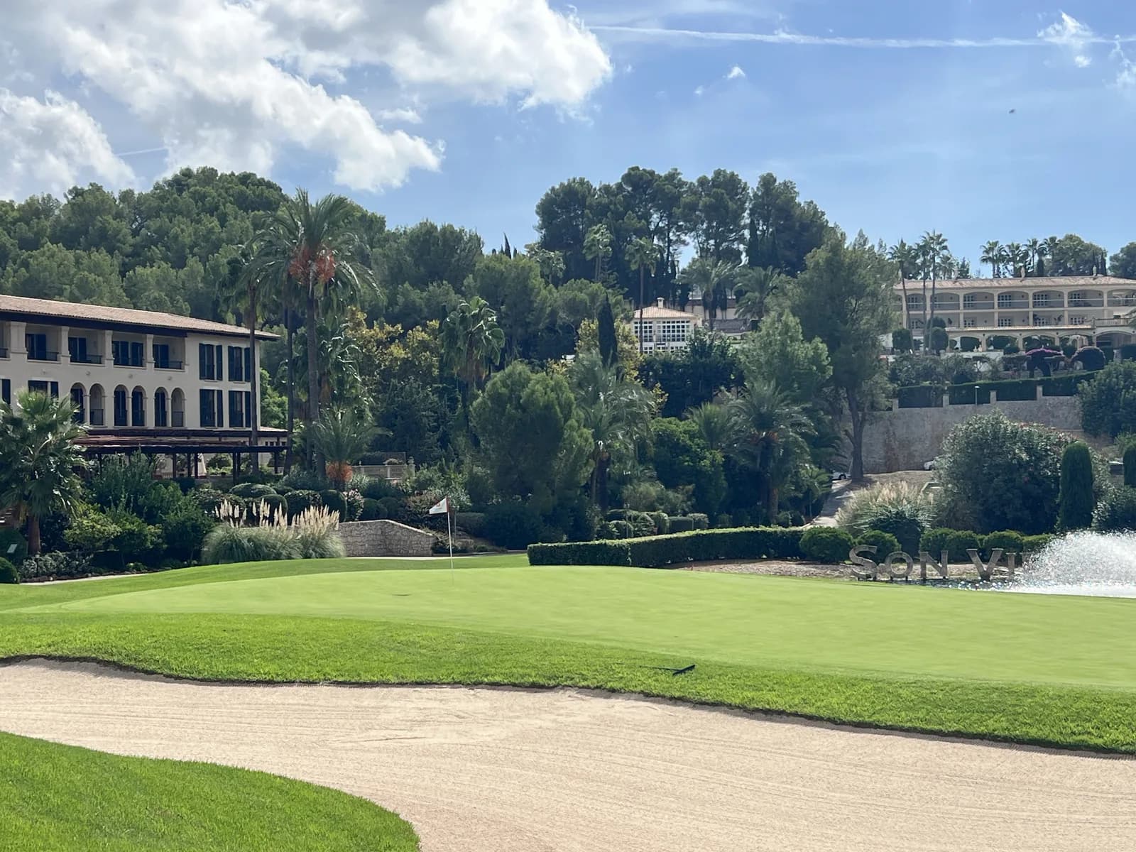 Green and bunker at Son Vida golf course Mallorca with the hotel behind and the Son Vida lettering beside a fountain