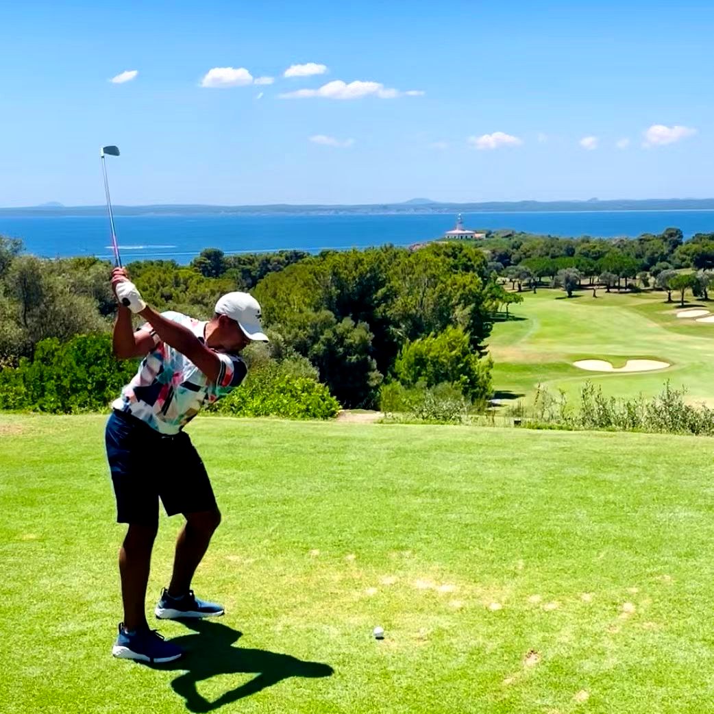Client hitting a tee shot at Alcanada with lighthouse in the background